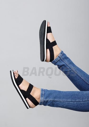 a woman's legs and feet in jeans and black sandals