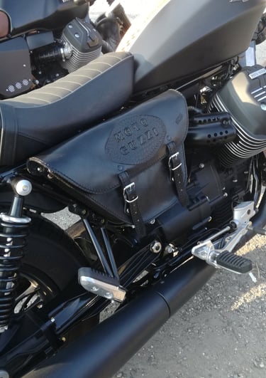 Borsa per moto nera con logo Guzzi di MaxCuoio. Ha due cinghie sul fronte, agganciata al lato di una moto Guzzi