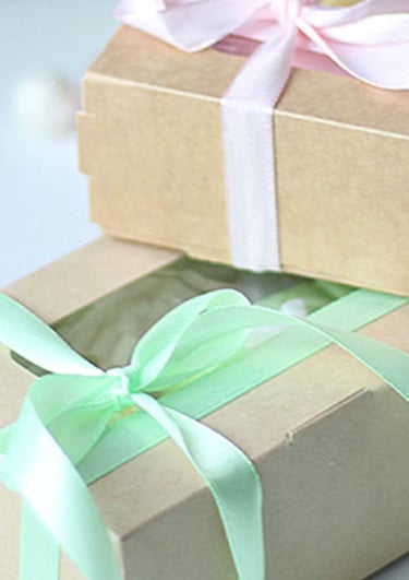 Handmade gift boxes in brown kraft paper with pastel pink and mint green ribbons.