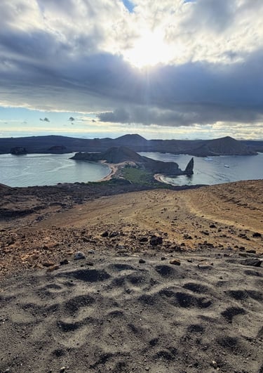 Panoramic view of Bartolome Island and Pinnacle Rock in the Galapagos Islands under a cloudy sky.