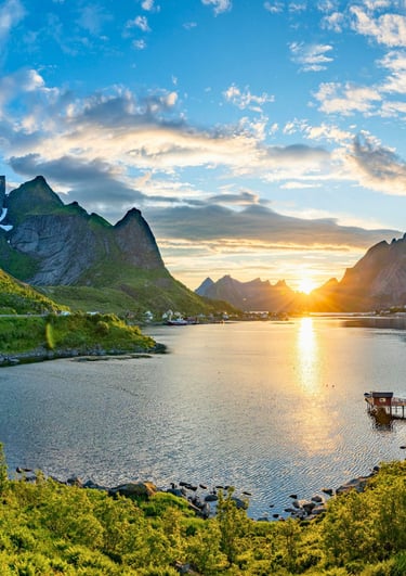 Scenic sunset over Reine village in Lofoten Islands, Norway, with mountains and coastal fjords.