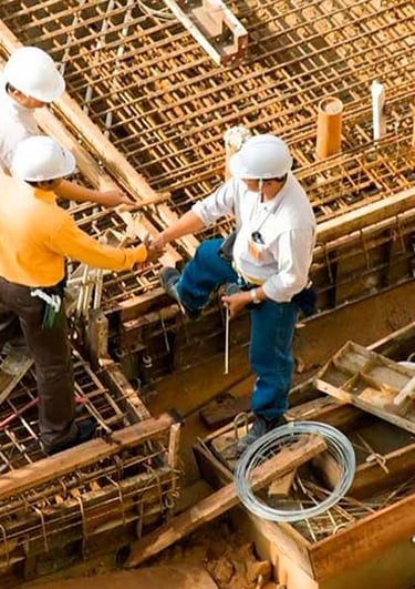 Profesionales revisando estructura en obra gris, reflejando ejecución de proyectos con calidad