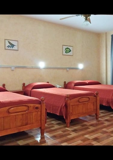Una habitación con tres camas y un ventilador de techo.