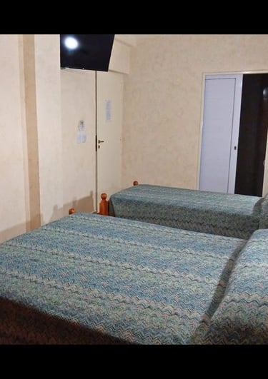 Una habitación con dos camas y un televisor de pantalla plana.