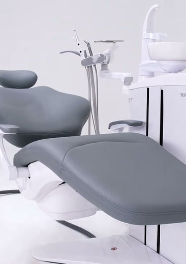 Modern ergonomic grey dental chair unit with professional tools in a clean clinic setting.