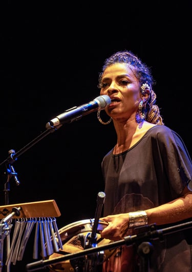 Cantora com um pandeiro na mão e microfone