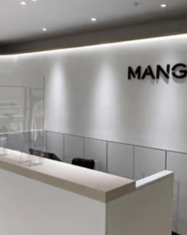 Minimalist interior of the Mango retail store, featuring microcement, a white checkout counter, and