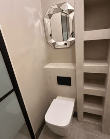 A modern bathroom with a private nook in textured beige, finished in microcement