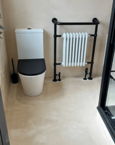 Modern bathroom with microcement walls, white toilet, black seat and black designer heated towel rai