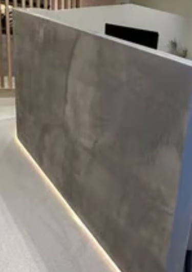A modern waiting room featuring a private, textured grey alcove finished in microcement, with recess