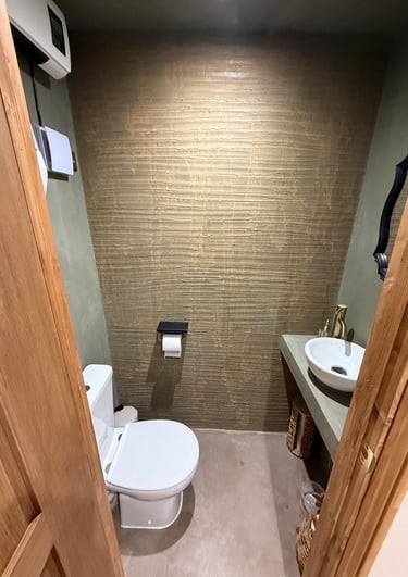 Rustic modern bathroom featuring a white vessel sink, gold faucet, and ornate black mirror.