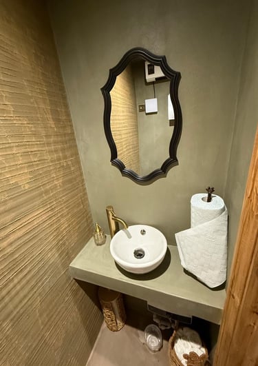 Rustic modern bathroom featuring a white vessel sink, gold faucet, and ornate black mirror.