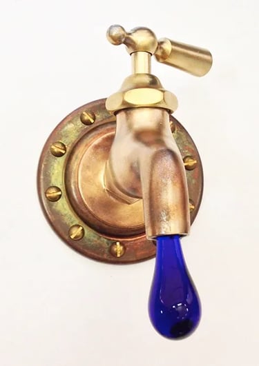 Vintage brass faucet with dark blue glass drip coming out ot the spout.