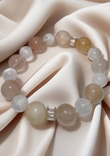 Elegant natural quartz gemstone bracelet with neutral round beads on draped silk fabric.