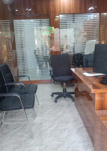 Professional office interior featuring a wooden desk, black rolling chairs, and glass partition doors.