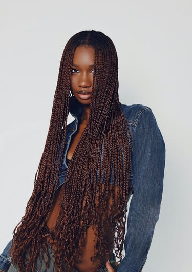 a dark woman with long hair box braids and a denim jacket