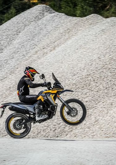 asmuo, važiuojantis motociklu žvyrkeliu