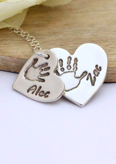 Double descending silver heart necklace with the handprint and names of 2 children.
