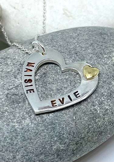A silver heart necklace personalised with 2 names on either side and a 24ct gold heart accent