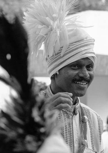 Smiling Indian man wearing a traditional turban and ethnic attire in a black and white portrait.