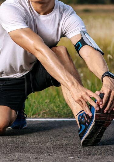 a man in a white shirt is stretching his legs on the ground