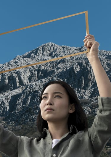 a woman holding a picture frame in front of a mountain
