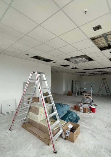 Sufit kasetonowy w trakcie montażu, duża sala z rusztowaniem i czarnymi panelami akustycznymi, płyty sufitowe w układzie pros