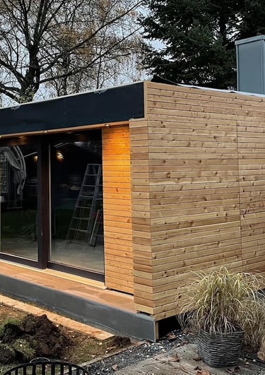 Wnętrze sauny z dużym oknem, drewniane ściany i sufit, podłoga z szarych płytek ceramicznych.