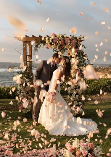 couple kissing under floral decorated arbor at cuvier park la jolla