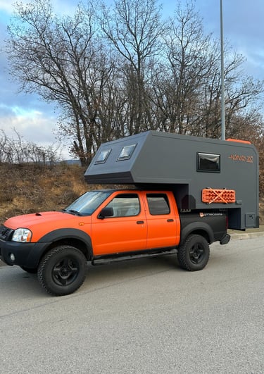 un vehículo pick up naranja con cabina camper