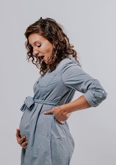 une femme enceinte qui regarde son ventre avec surprise