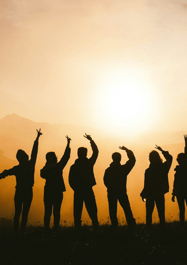 Silhouette of people on a mountain representing group lessons to improve proficiency and have fun