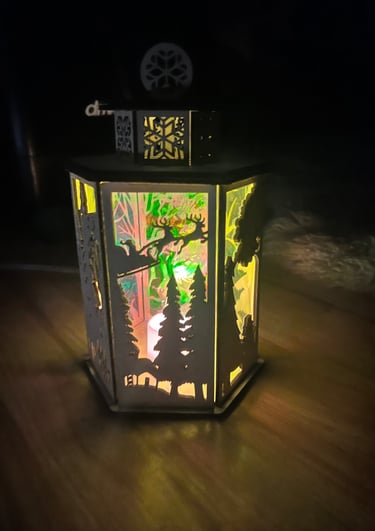Glowing decorative lantern with cutout forest and deer scenes.
