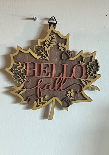 Leaf-shaped wooden wall sign saying "Hello Fall" with acorn and leaf accents.