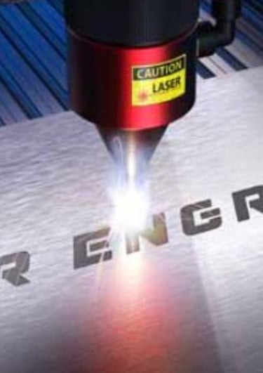 Una máquina de grabado láser en el proceso de grabado de una placa de metal.