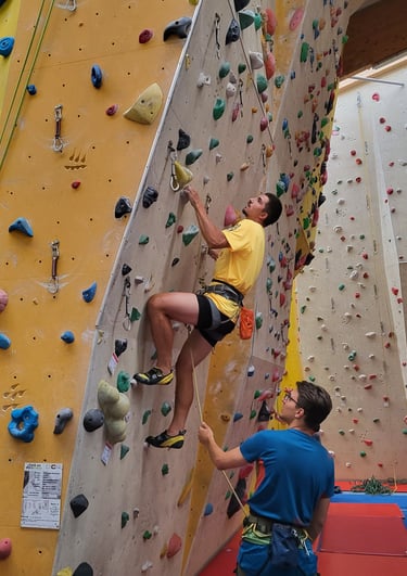 An indoor climbing course participant climbs on lead.