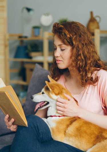 woman in her 20s reading book relaxing with dog in lap shiba inu