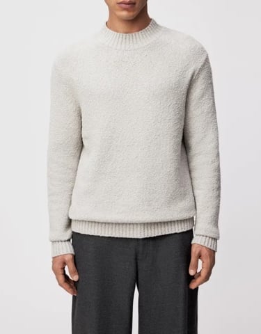 a man in a white sweater and pants with a grey sweater