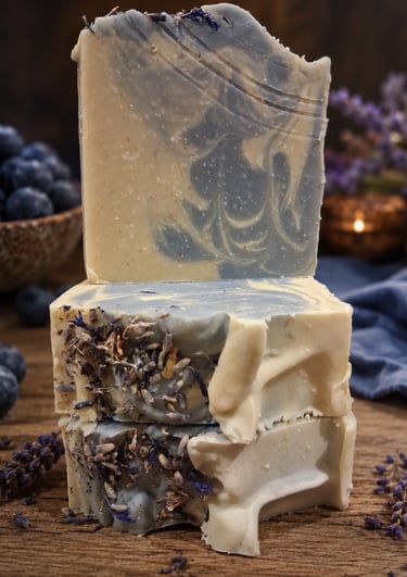 Handmade blueberry soap bars stacked on a rustic wood table with fresh berries.