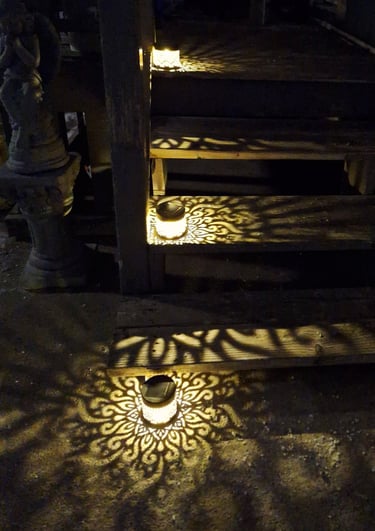Solar lanterns casting decorative mandala patterns on outdoor wooden garden steps at night.