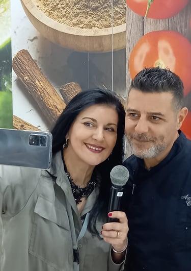 Clara Mennella intervista lo chef Armando Codispoti durante un evento gastronomico, riprendendo con smartphone e microfono.