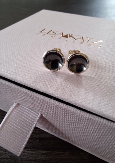 Handmade silver and dark gemstone stud earrings displayed on a pink Lisa Katz Jewellery box.
