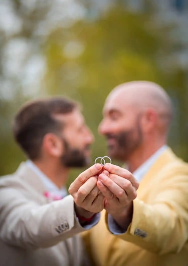 "Pareja gay casada mostrando sus anillos de boda en Madrid, celebrando su amor y unión."