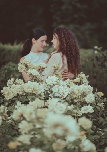 "Pareja lesbiana con flores de rosa blanca, celebrando su compromiso en una boda gay."