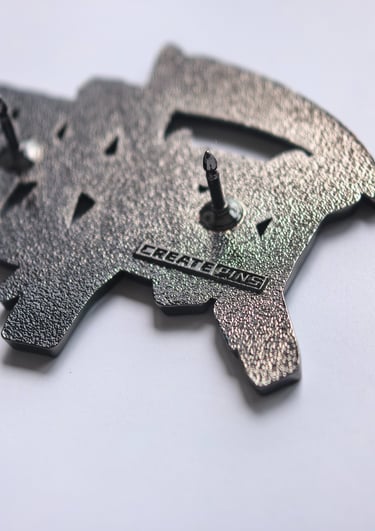 Back of a textured custom enamel pin featuring dual posts and a stamped logo for branding.
