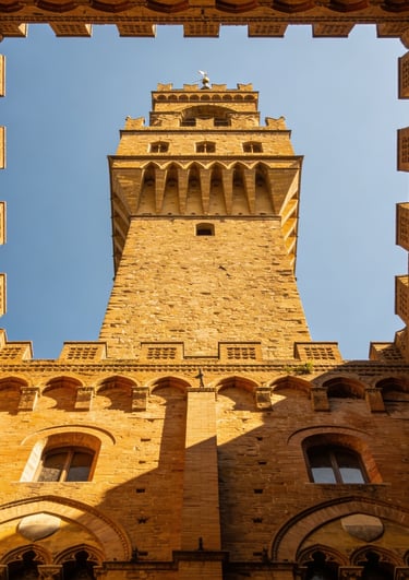 Low angle view of the historic Palazzo Vecchio tower against a blue sky in Florence, Italy.
