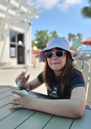 a woman in a hat and sunglasses sitting at a table