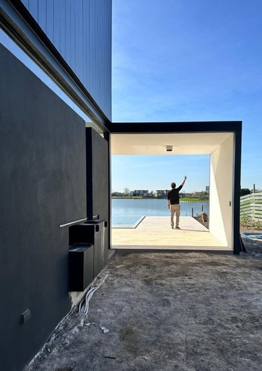  Un hombre parado frente a un edificio con vista a un cuerpo de agua.