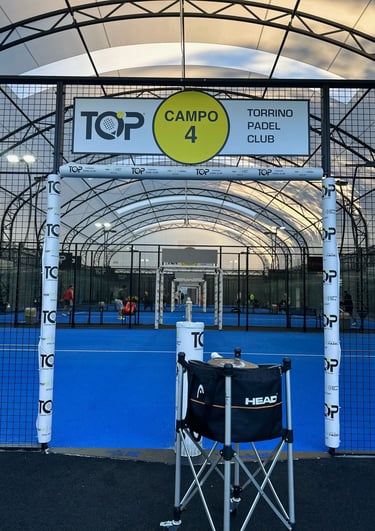 Indoor blue turf padel court at Torrino Padel Club with Head ball basket in the foreground.