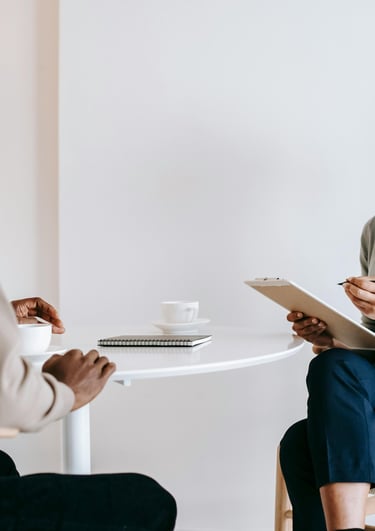 Une femme assise à une table et un homme sur une chaise en train de discuter